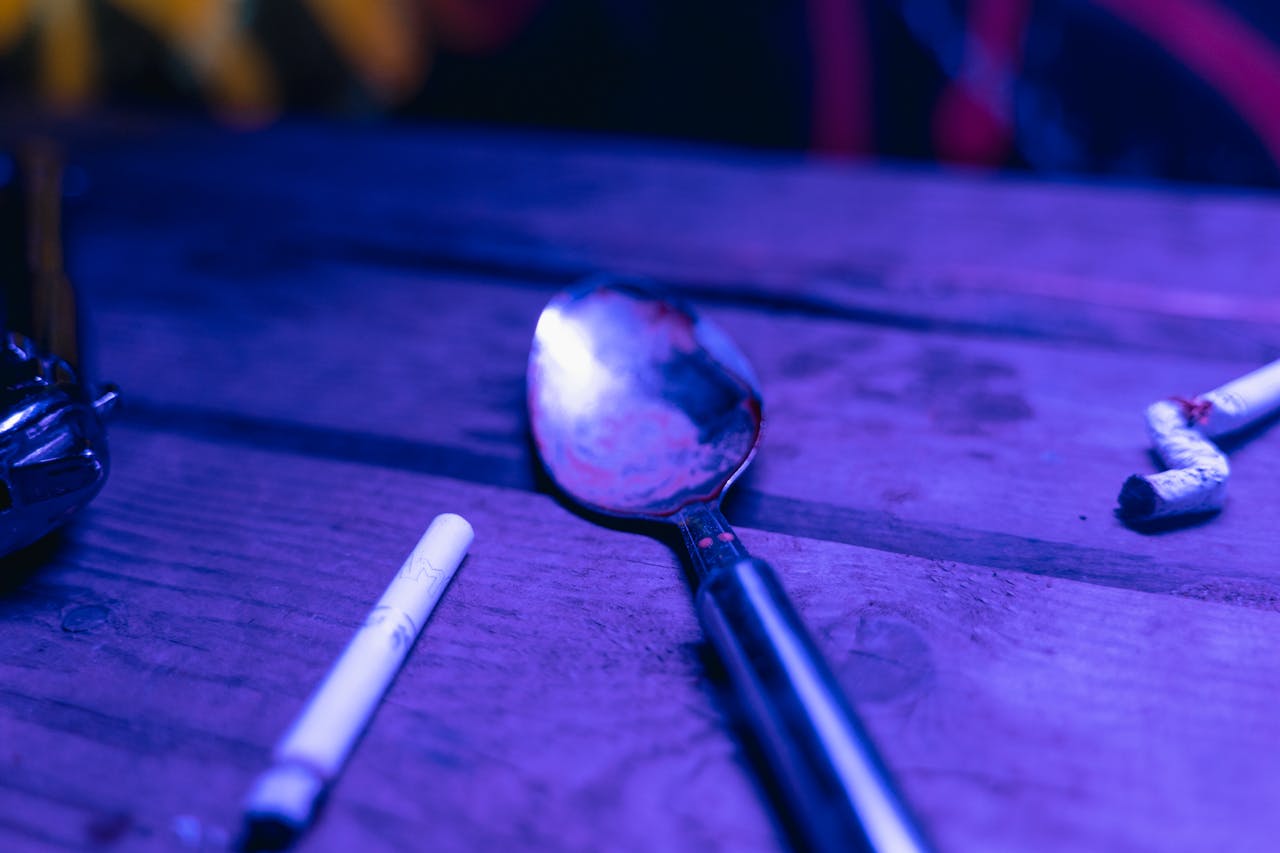 Dramatic depiction of potential drug use with spoon and cigarette in moody lighting.